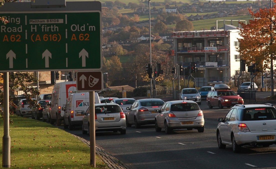 traffic jam with multiple lanes of cars in standstill, next to a road sign indicating lanes for different destinations