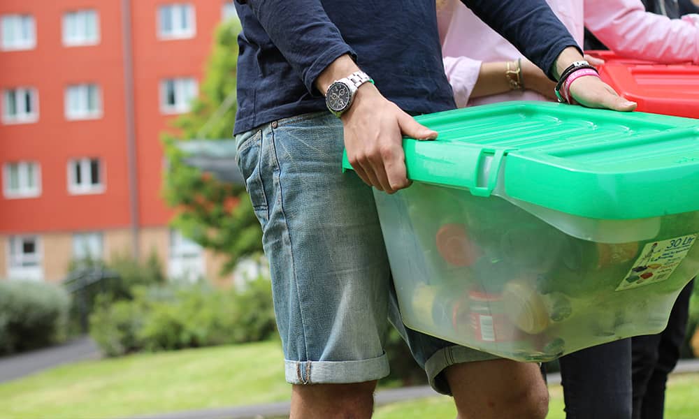 Student carrying a recycling box outside to the bin store