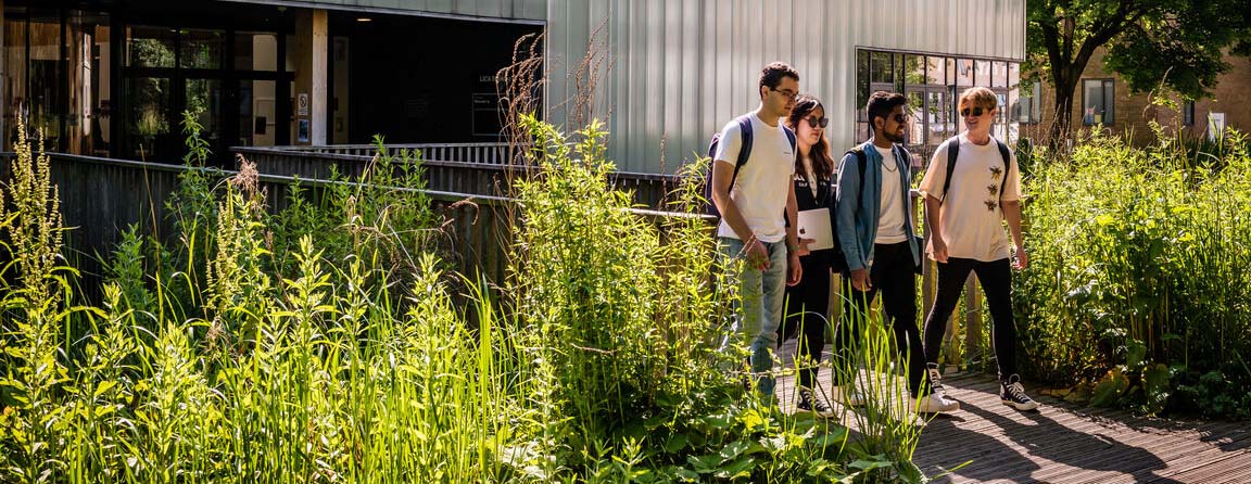 Four students walking out of LICA surrounded by greenery