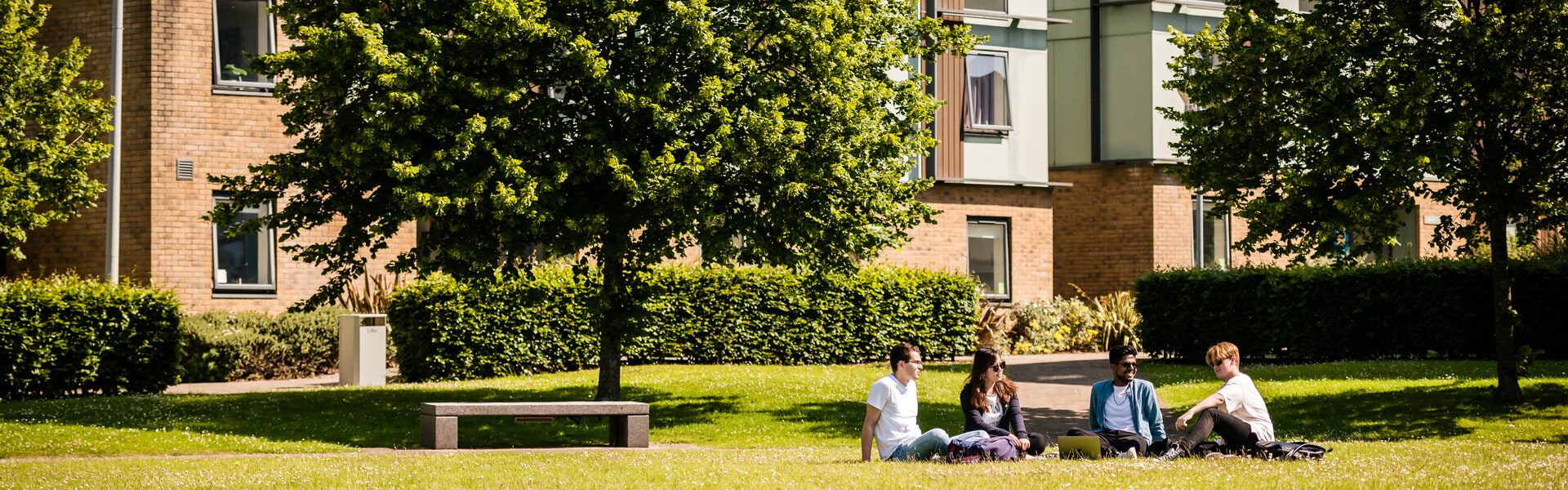 Four students sat on the grass outside County house accommodation