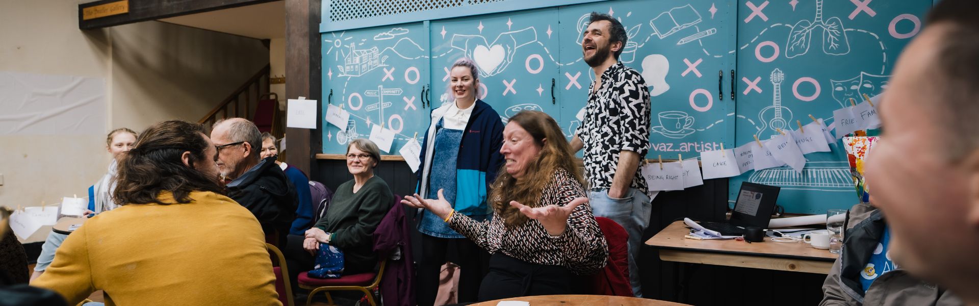 a group of people, some sitting, some standing, taking place in a discussion workshop