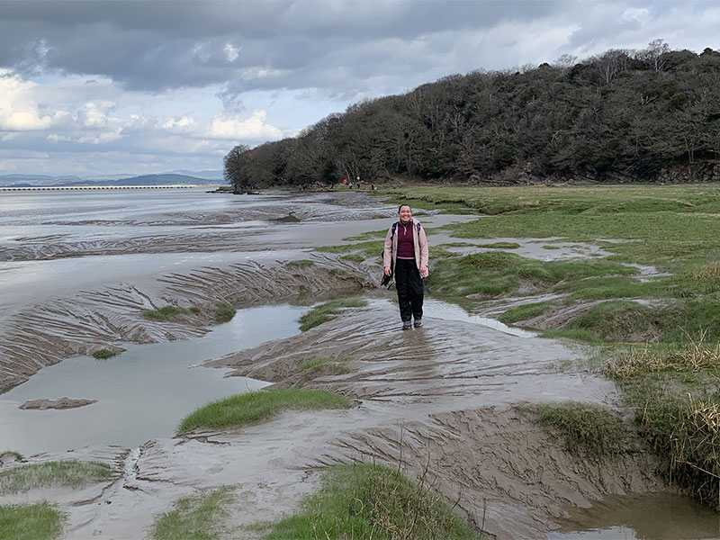 Student Lyea stands smiling on the beachside in Arnside.