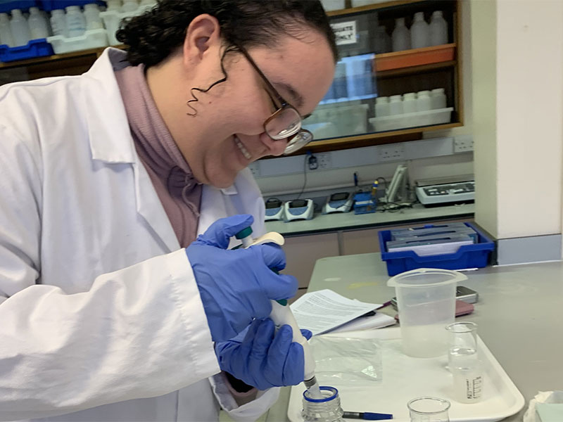 Student Lyea in a lab wearing a lab coat.