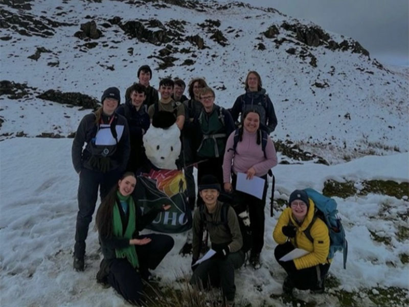 Student Lyea with other students standing by a snowman.