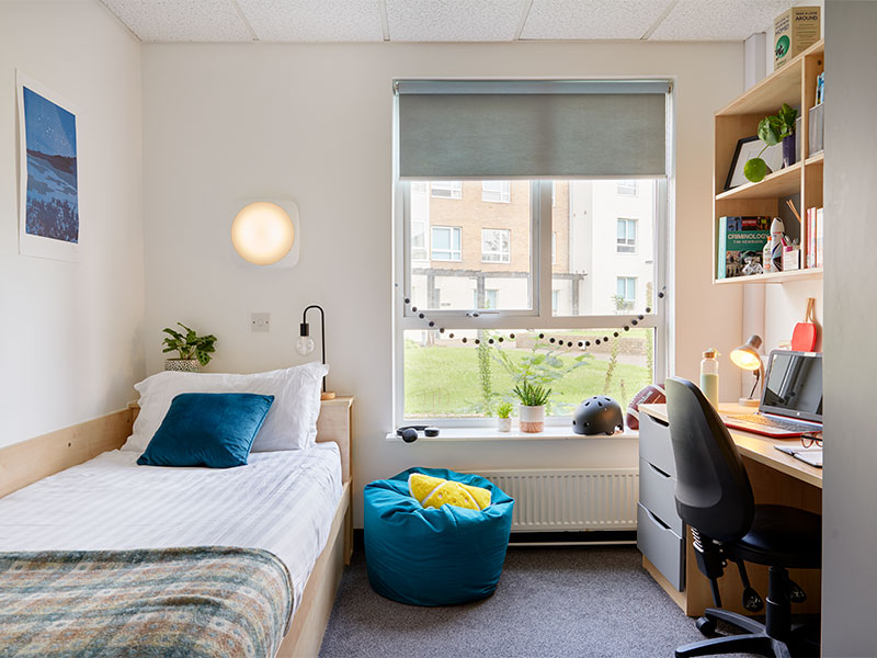 Pendle College accommodation - room with single bed, desk and chair with decorations.