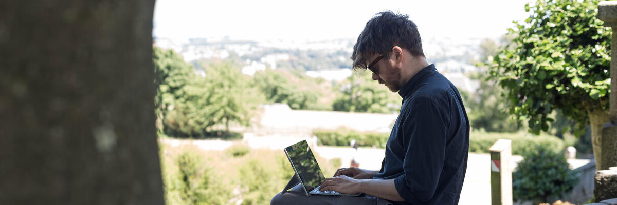 A student on a laptop in the Storey in front of a stained glass window