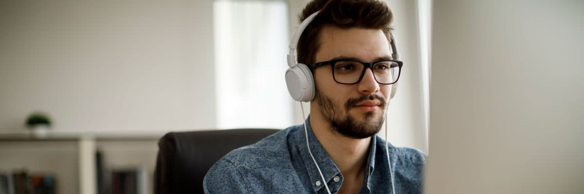 Young man working at computer wearing headphones