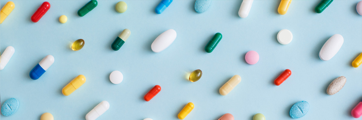 Different pills organised against a blue background