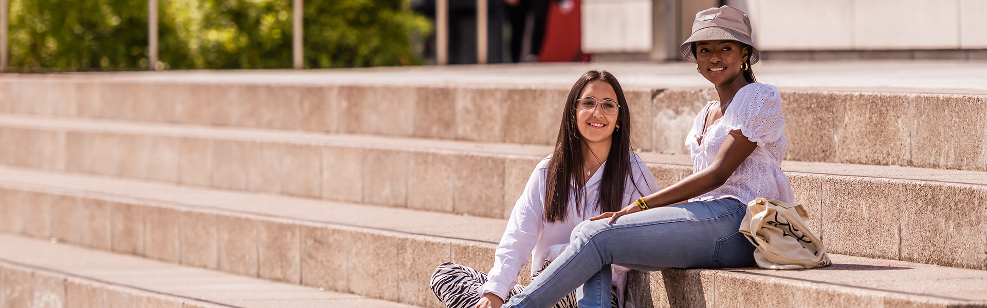 two students sitting on a bench surrounded by greenery at Lancaster university 