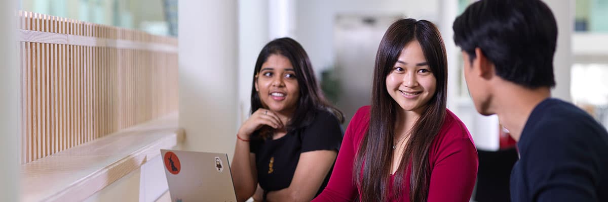 Students working at laptops and chatting in a modern university building