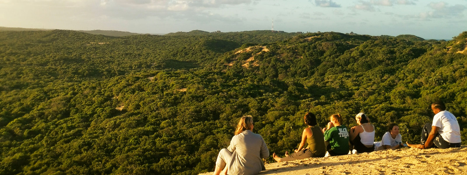 Students lying on the summit of the tallest mountain in Mozambique, looking out over an African hillscape