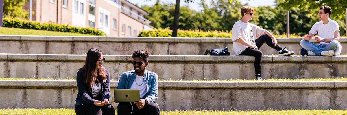 Lancaster University students studying on campus outside in the sunshine