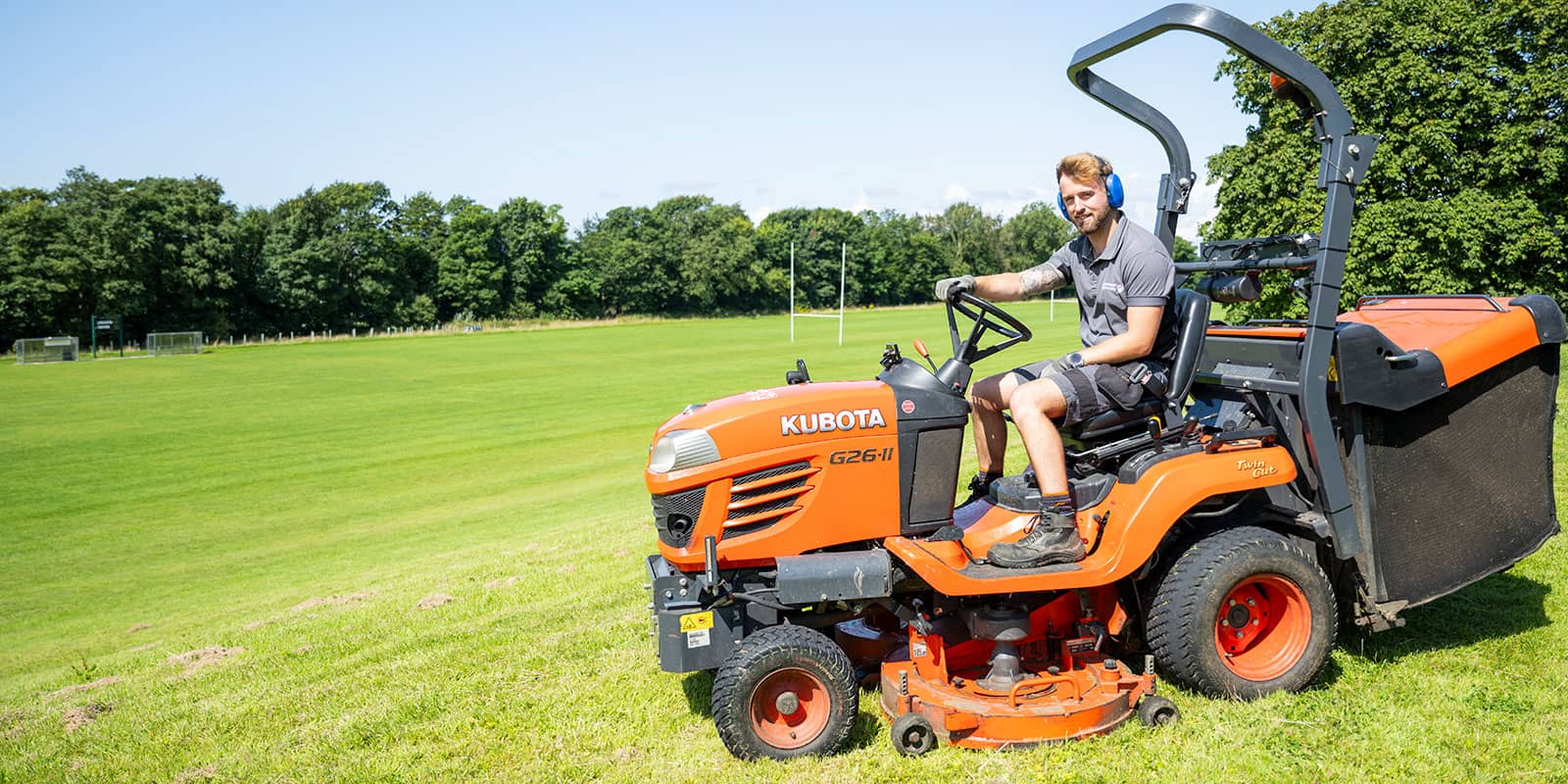 A man sitting on a large orange Kubota lawnmower.