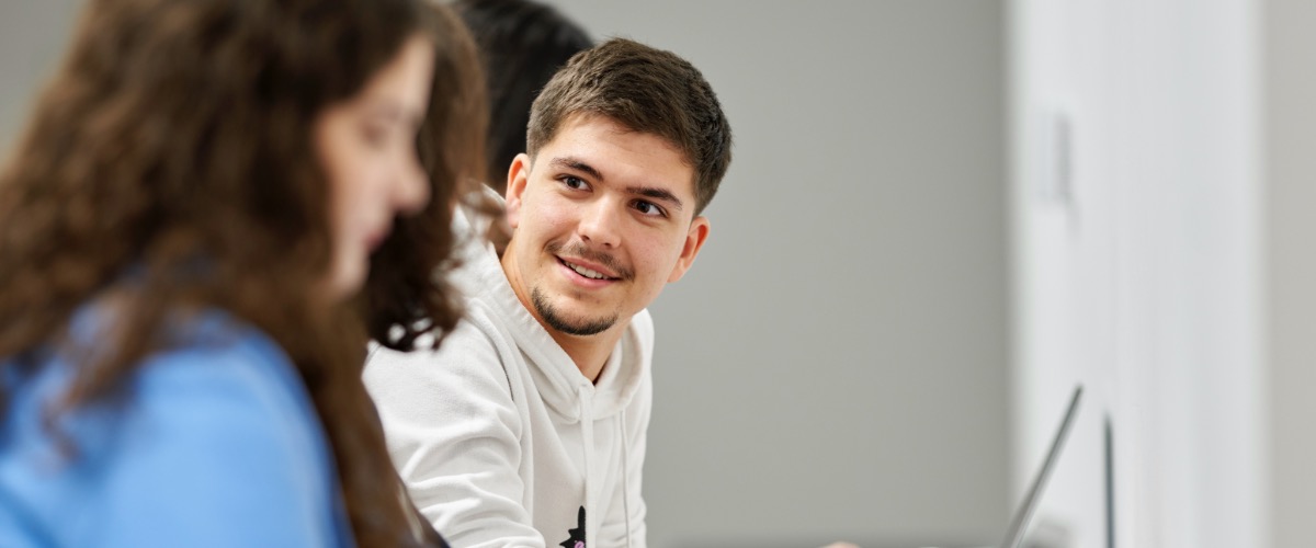 A row of students at a laptop each