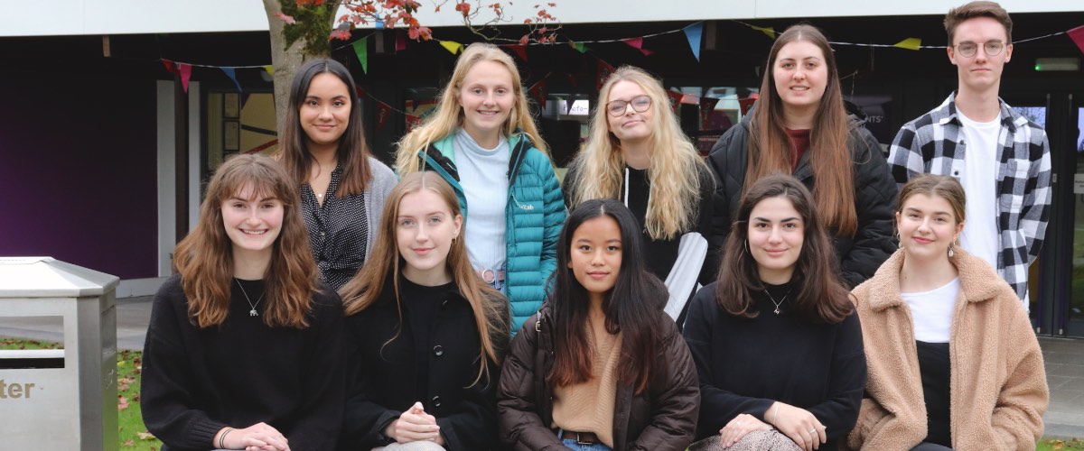 Student content creators sit in two rows to pose for a photograph