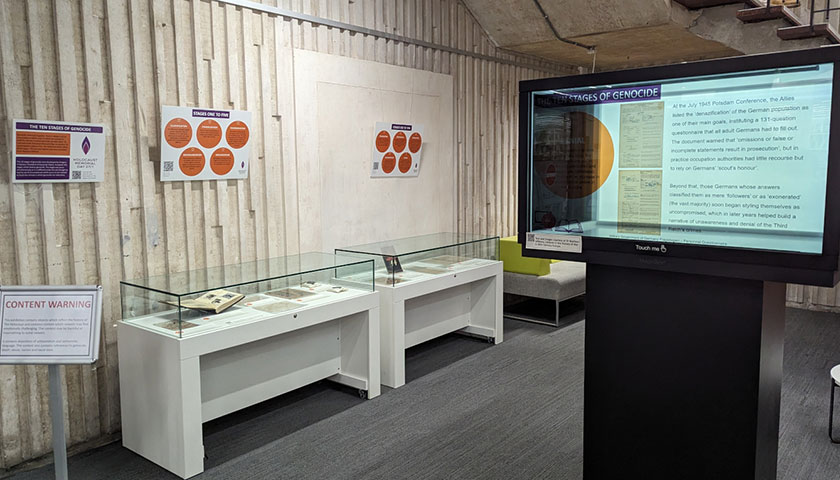 Holocaust Memorial Day 2024 exhibition featuring boards and objects in cabinets.