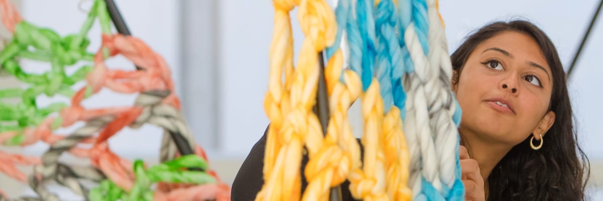 A student works on a large textile installation in the Degree Show.