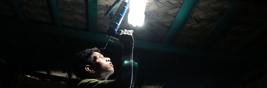 A bottle lamp being installed in a shanty town home.