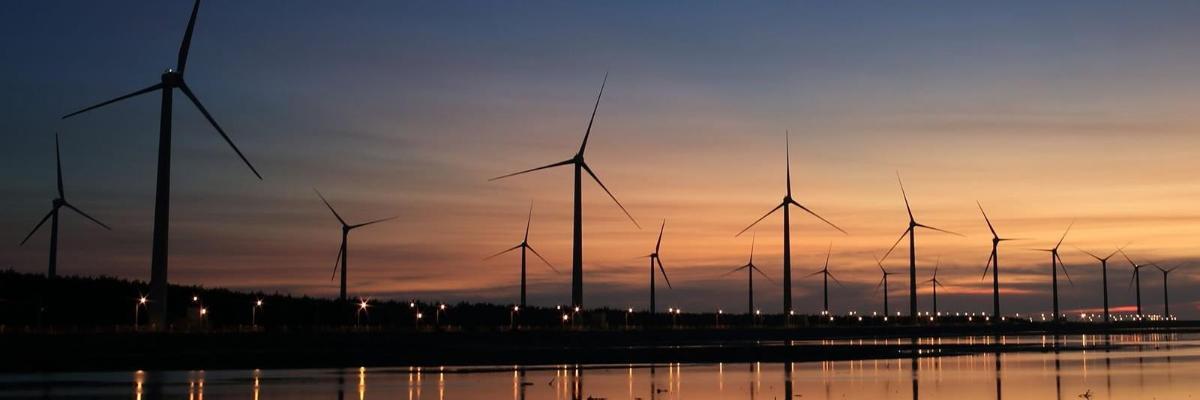 Wind turbines silhouetted against a sunset