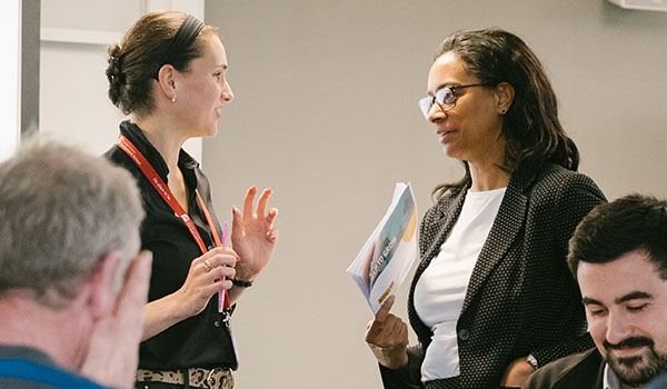 Man in suit jacket speaking to a colleague in a meeting room