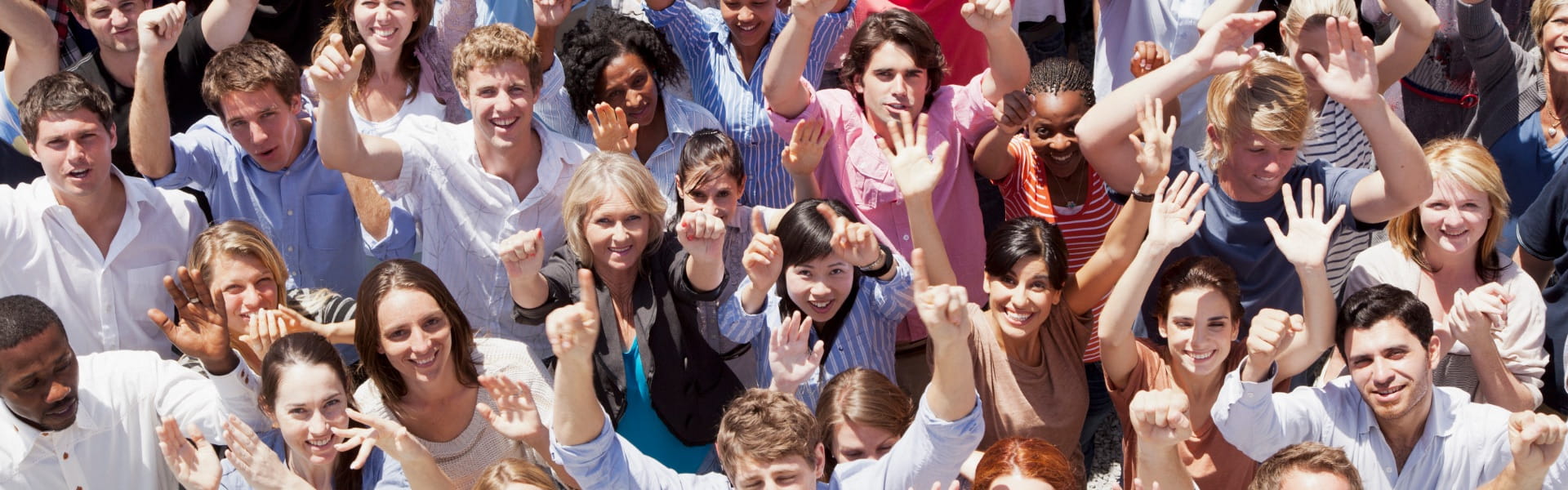 A crowd of people, photographed from above, raise their hands towards the viewer.