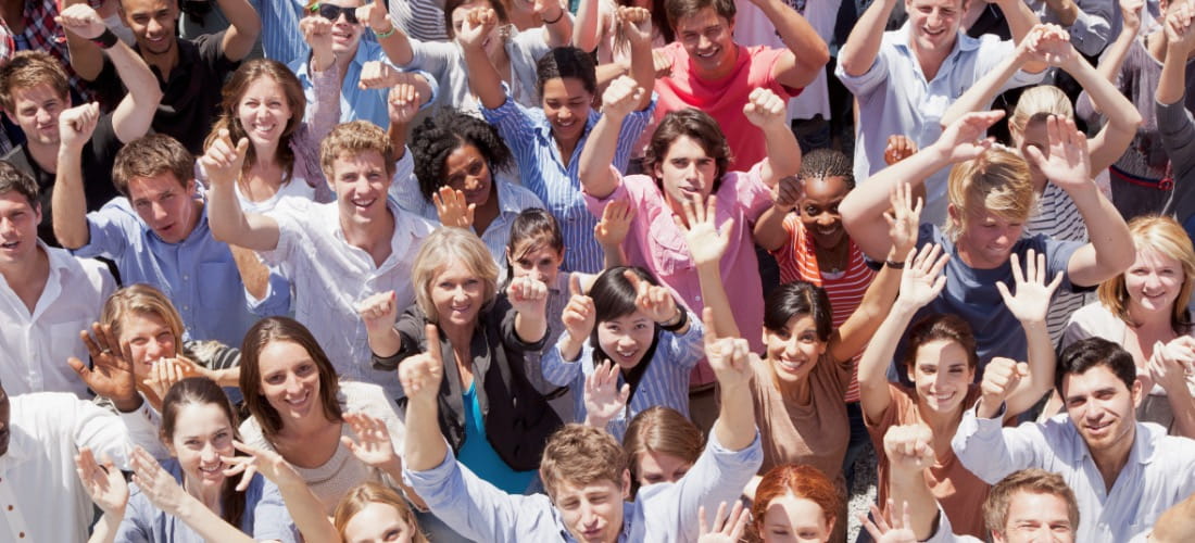 A crowd of people raise their hands.