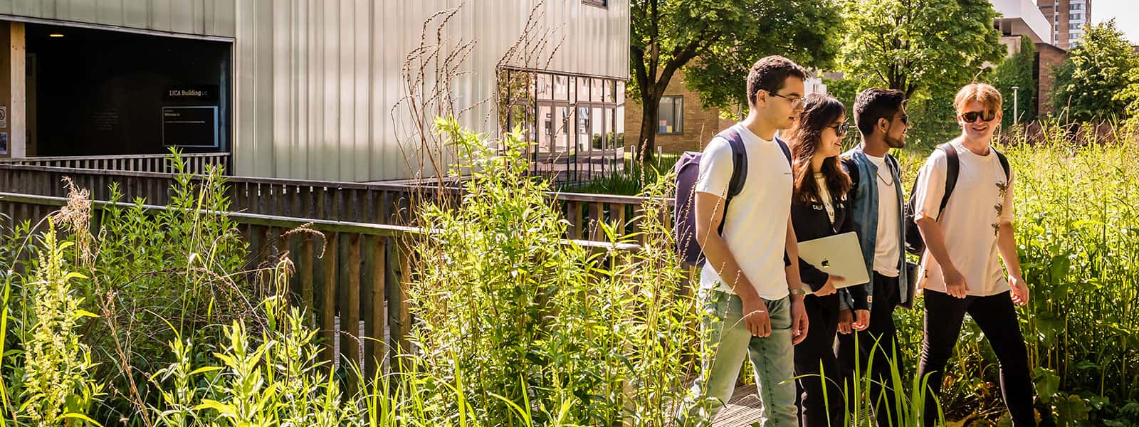 Students walking and talking with lush green plants in the foreground