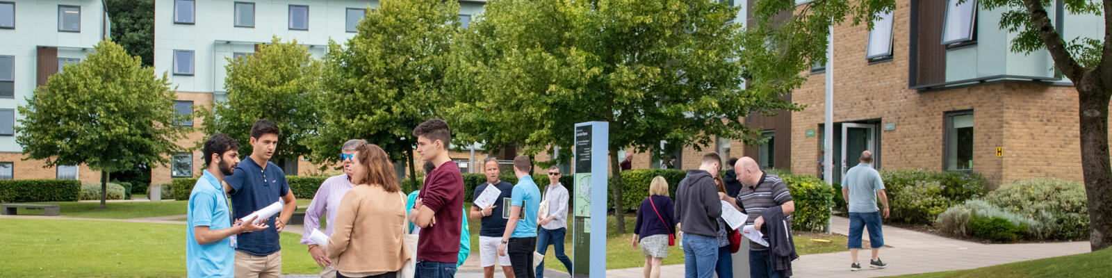 Campus tour groups in Lancaster Square with trees and residences in the background