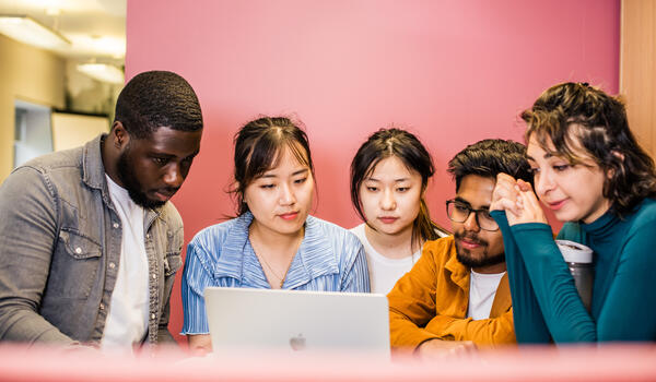 Students collaborating in front of a laptop