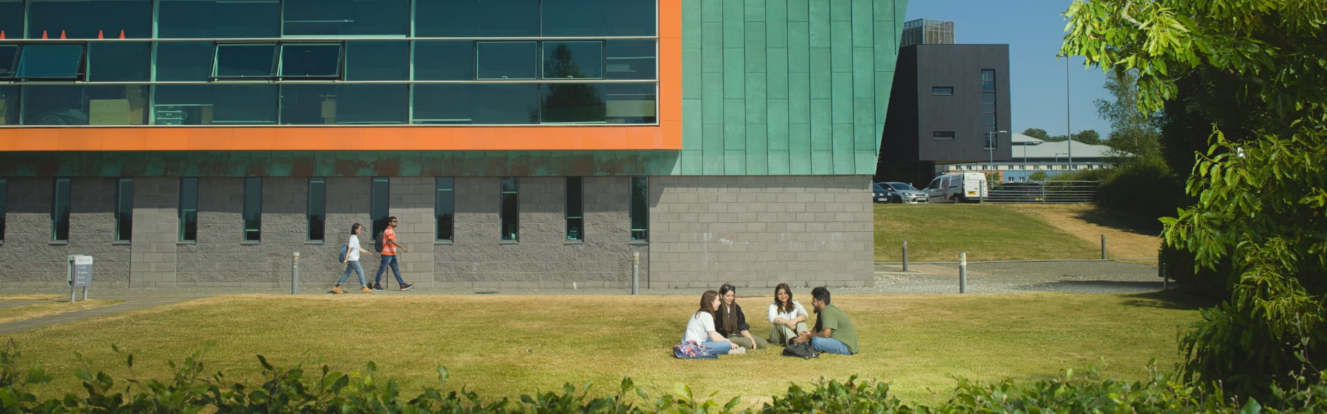 Students sit on the grass around the south side of the InfoLab building