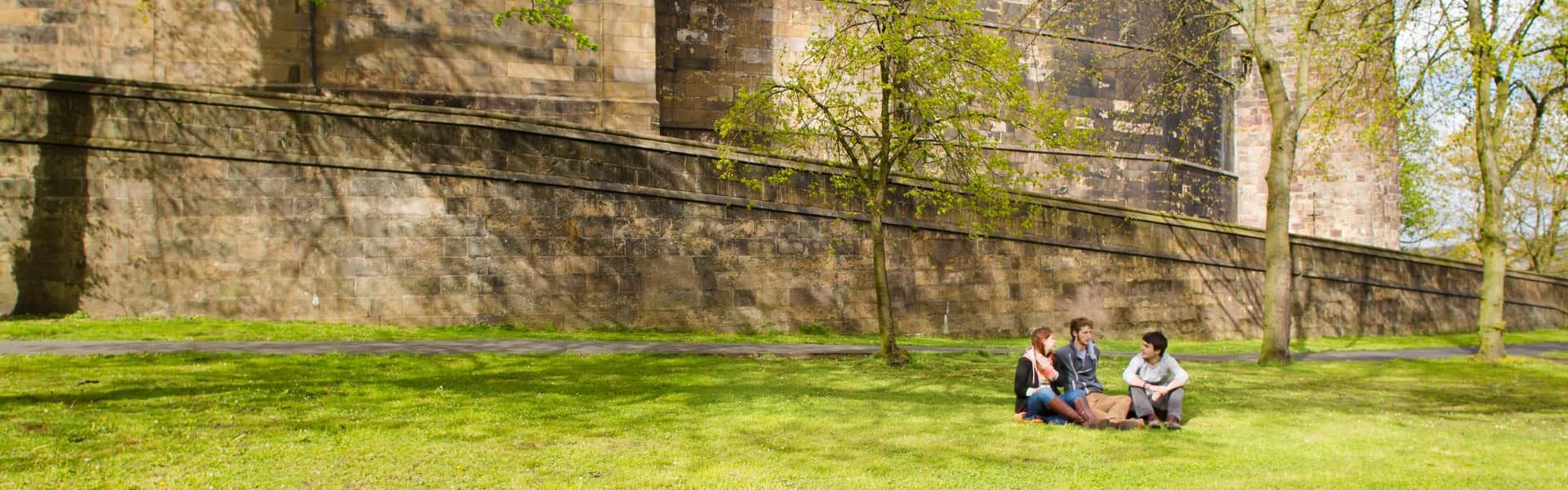 Students sit on the grass by the castle in the city centre.