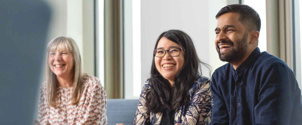 Two students in the Management School sit at desks laughing.