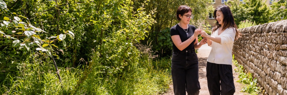 Two students walk by a dry stone wall near the Ecohub.